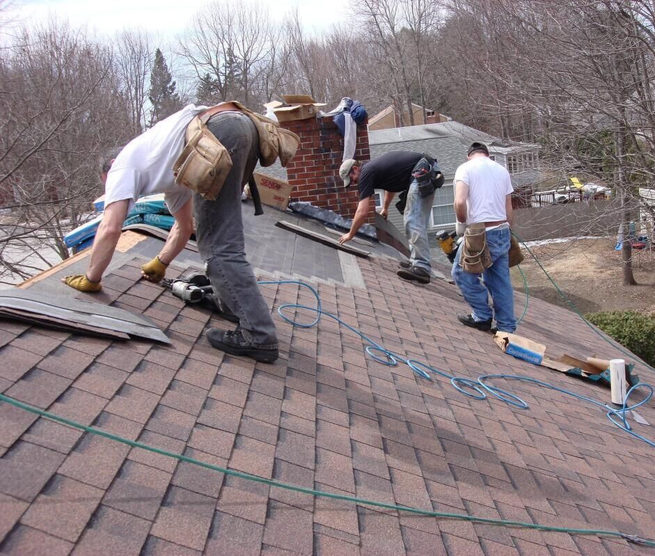 A large roofing team repairing a fooftop in a neighborhood