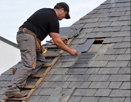 A roofing inspector checking the grout underneath a shingle on a home