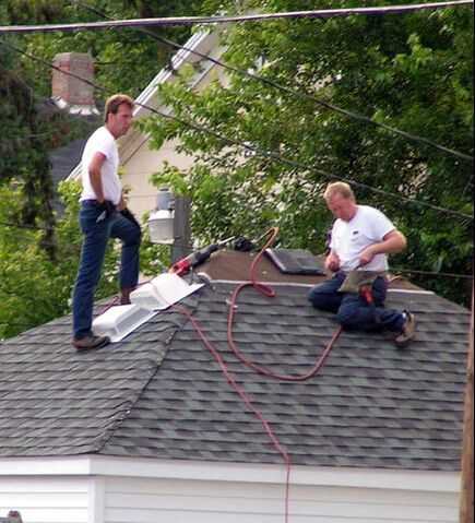 Two men with power tools on a rooftop